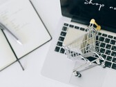 Carrito de la compra en miniatura sobre el teclado de un ordenador portátil, con el mensaje «Comprar ahora» en la pantalla