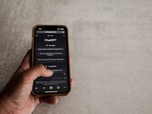 Mano sosteniendo un smartphone que muestra la interfaz de ChatGPT sobre una superficie de piedra gris