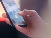 Una mano sostiene un smartphone y lo desbloquea mediante el sensor de huellas dactilares de la pantalla de bloqueo.