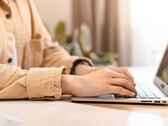 Unas manos tecleando en el teclado de un ordenador portátil abierto sobre un escritorio bien iluminado
