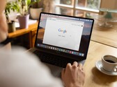 Persona frente a una computadora portátil con la página principal de Google abierta, junto a una taza de café