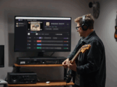 Un guitarrista toca frente a un monitor que muestra la aplicación StemKit.