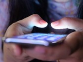 Dos manos sostienen un smartphone con la pantalla iluminada en la penumbra
